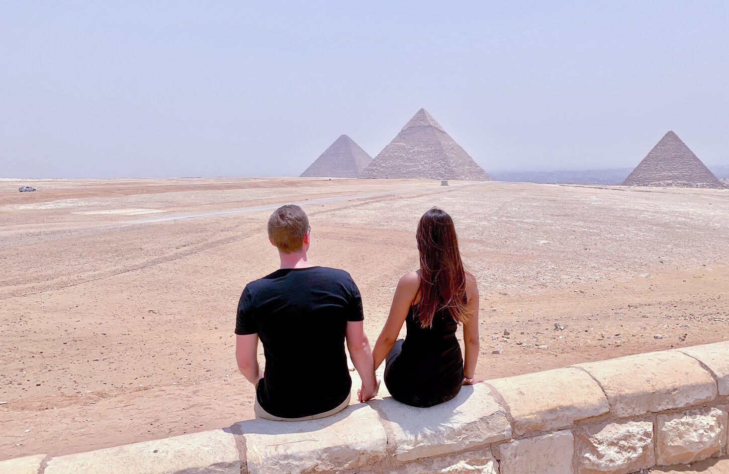 A picture of a couple in front of the pyramids of Giza
